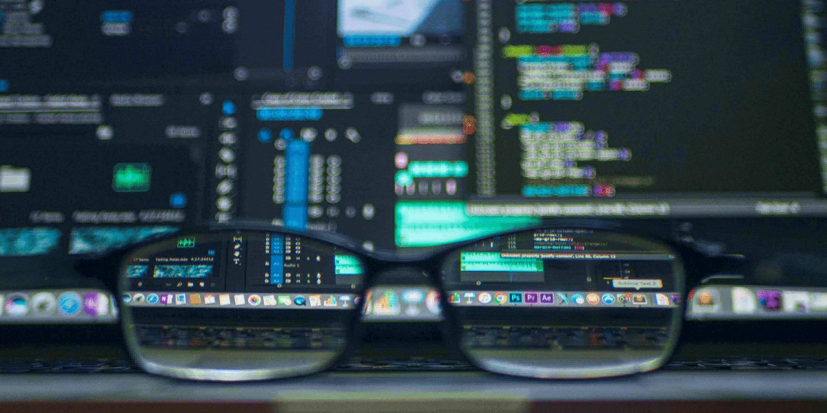 Close up of reading glasses by a computer screen full of code