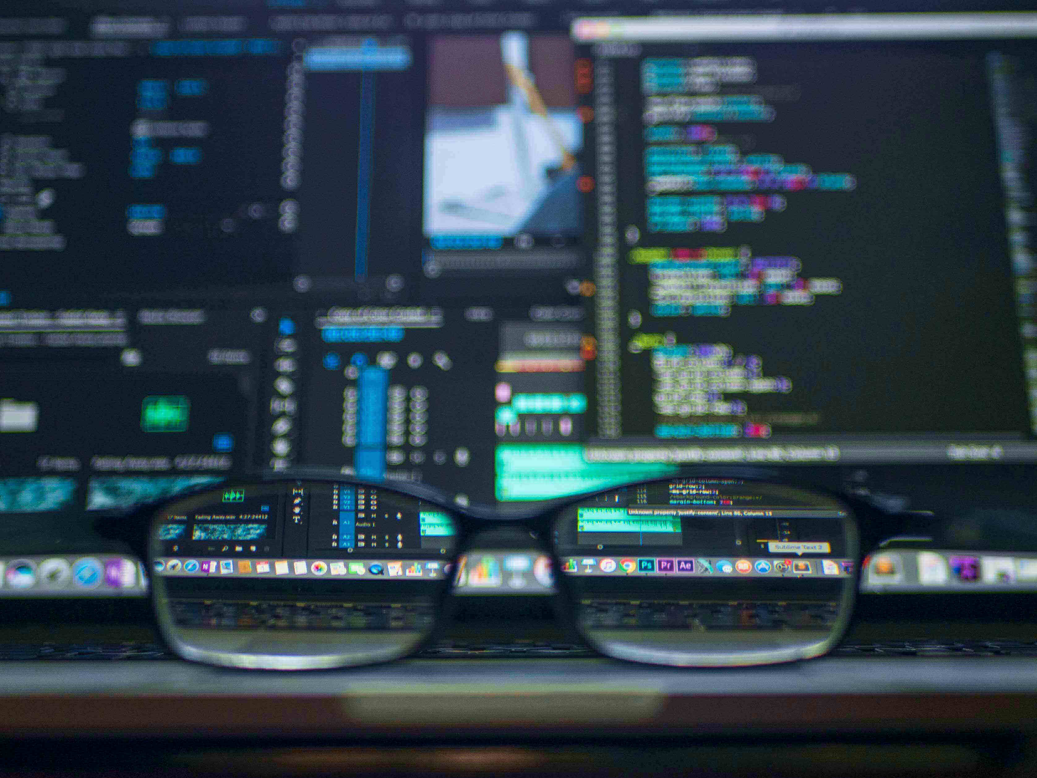 Close up of reading glasses by a computer screen full of code